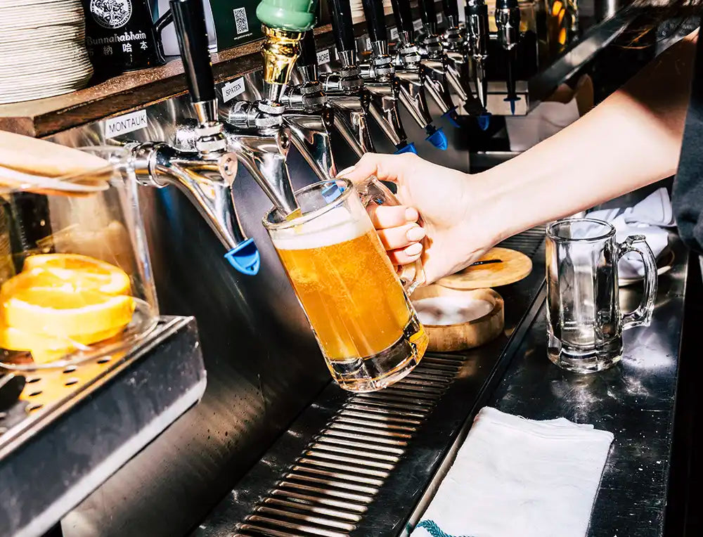 Beer mug being filled up on draft inside of a bar