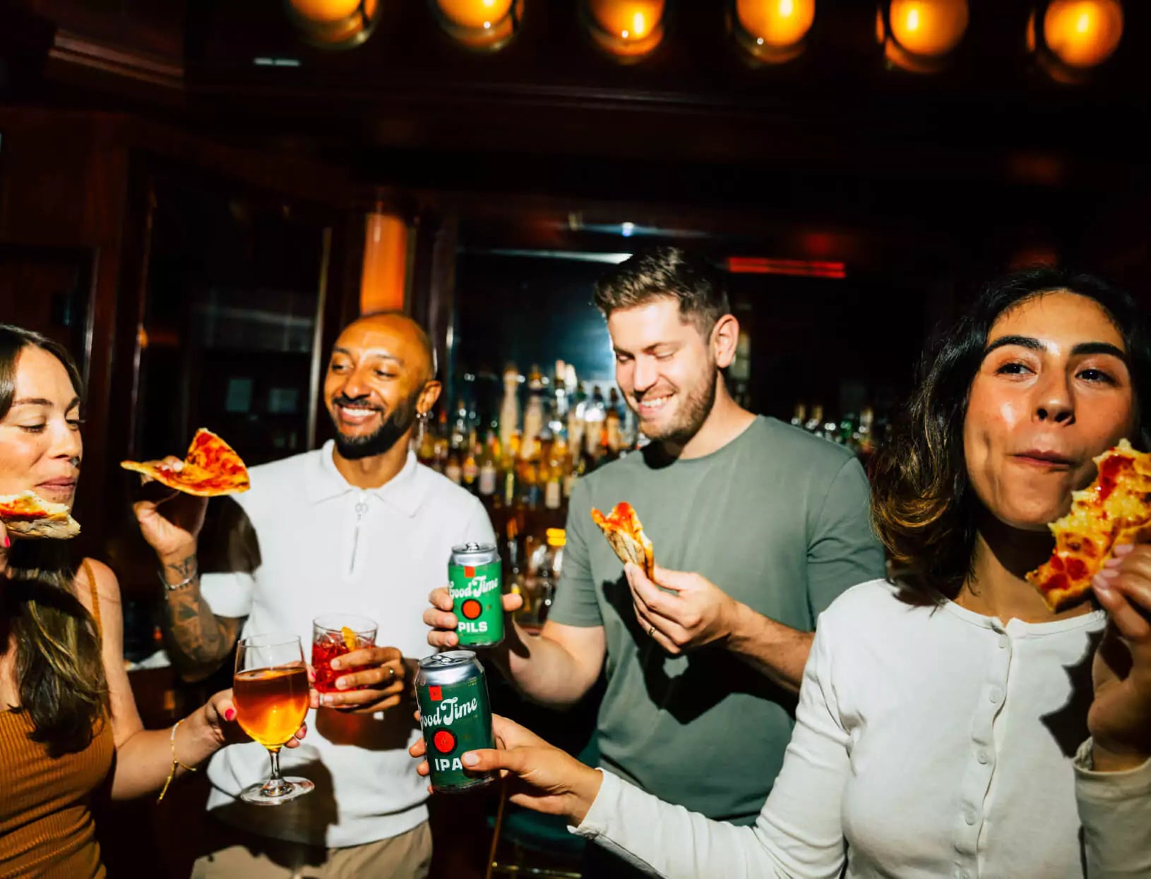 Some friends enjoying Good Time Brewing Co.'s IPA and Pils at a bar while eating pizza.